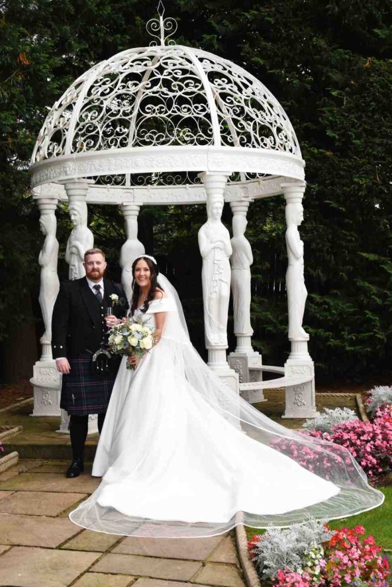 Natural wedding photography Central Scotland: Groom dipping and kissing the bride in an outdoor pavilion